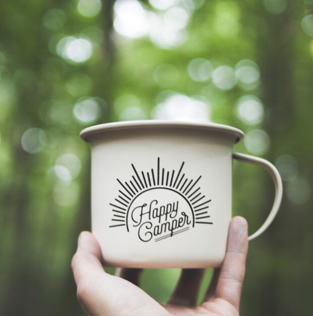 Etude de projet - gros-plan-tasse-metal-blanc-happy-camper-ecrit-surface-bois-pres-plantes-vertes